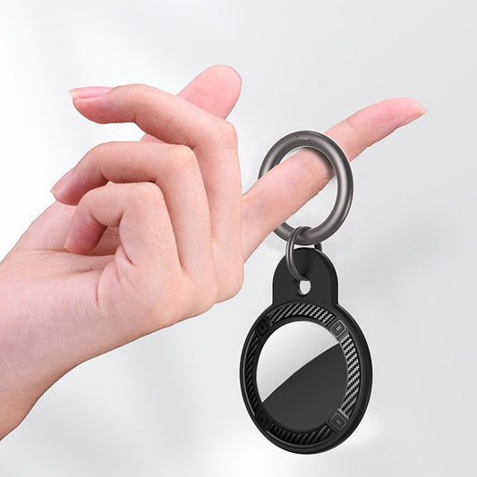 Carbon fiber AirTag case in-use on backpack keychain, compact round design for travel security